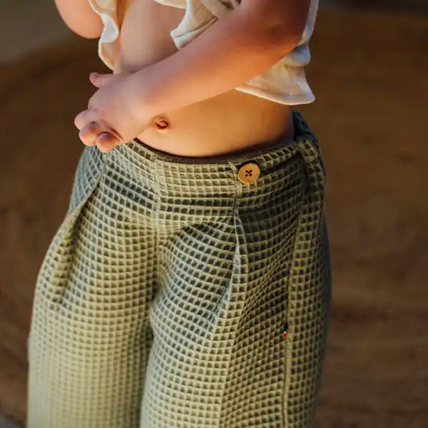 Pantalon bébé nid d'abeille kaki en coton bio. Coupe ample et style pantalon à pont.